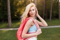 Charming sexy young woman in fashionable sportswear with stylish pink backpack walks on woods at sunset. Beautiful blonde girl Royalty Free Stock Photo