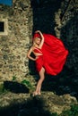 Charming sexy young woman in fluttering red dress. stone background. Fashion photo of young magnificent woman in red Royalty Free Stock Photo