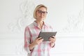 Charming short-haired woman in glasses holds tablet in her hands and smiling