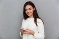 Charming smiling girl holding mobile phone and looking at camera Royalty Free Stock Photo