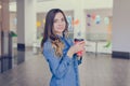 Charming smiling happy woman dressed in jeans shirt is drinking latte while doing shopping in a mall takeaway coffee shop to go wa Royalty Free Stock Photo