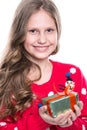 Charming smiling little girl with curly hairstyle wearing red knitted sweater and holding christmas gift isolated on white. Royalty Free Stock Photo