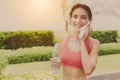 Charming sport woman hold bottle of drinking water, use towel wipe sweat after jogging. Attractive beautiful girl taking a rest be Royalty Free Stock Photo