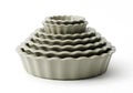Stack of fluted ceramic tart pans in graduated sizes for baking delicious pastries isolated on white background Royalty Free Stock Photo
