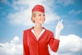 Charming Stewardess Dressed In Red Uniform Pointing The Finger. Royalty Free Stock Photo