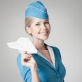 Charming Stewardess Holding Paper Plane In Hand. Gray Background