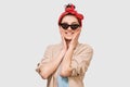 Charming student girl smiling broadly, wears beige shirt, red headband and black sunglasses. Pretty positive young woman feels