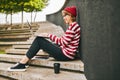 Student girl in earphones sits outside on staircase with laptop, notebooks and takeaway coffee Royalty Free Stock Photo