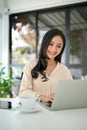 Charming Asian businesswoman using laptop, typing on keyboard, working on her business tasks Royalty Free Stock Photo