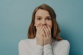 Charming surprised positive young woman closing her mouth with both hands in excitement Royalty Free Stock Photo