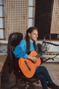 Charming talented African young woman musician songwriter singer plays guitar and records new song in the music studio