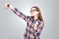 Charming teenage girl in glasses taking selfie with cell phone