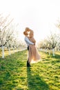 Charming tender loving couple walking in a spring blossoming garden at sunrise. Man whirls woman in her arms. Love story Royalty Free Stock Photo