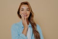 Charming tender woman touches cheek gently with hand in studio background