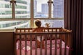 a charming toddler looks out the window at the metropolis while standing in a crib. baby in a crib looks out the window