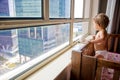 a charming toddler looks out the window at the metropolis while standing in a crib. baby in a crib looks out the window