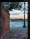 Charming view of the lagoon in Venice, Italy framed by a brick wall and a street light. Royalty Free Stock Photo