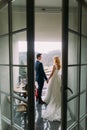 Charming wedding couple standing and holding hands on balcony. Back view