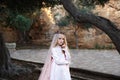 Charming white witch foreteller stands in a mysterious magical forest in a wedding dress with a veil and crown