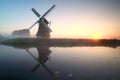 Charming windmill by lake at sunrise