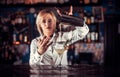 Charming woman bartending mixes a cocktail at the bar counter