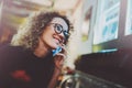 Charming woman with beautiful smile making call via her mobile phone during rest in coffee shop. Bokeh and flares effect Royalty Free Stock Photo