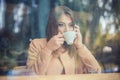 Charming woman with beautiful smile reading good news on mobile phone during rest in coffee shop, happy Caucasian female watching Royalty Free Stock Photo