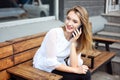 Charming woman with a beautiful smile speaks good news on a mobile phone while relaxing in a cafe, a happy Caucasian Royalty Free Stock Photo