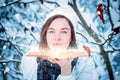 Charming woman blows bright dust from the pages of a book in the winter forest. Fairy tale concept. Christmas. New Year`s holiday Royalty Free Stock Photo