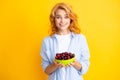 Charming woman with cherry plate isolated on yellow.