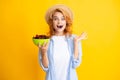 Charming woman with cherry plate isolated on yellow.