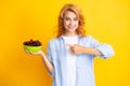 Charming woman with cherry plate isolated on yellow.