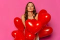 Charming woman posing at camera with red balloons.