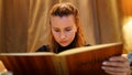 Charming woman sitting by table and mindfully reading book