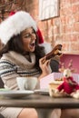 Charming woman wearing Santa Claus hat opening Christmas gift Royalty Free Stock Photo