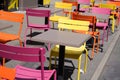 Charming yellow orange and pink chairs on cafe outdoor restaurant cafe and wooden tables colorful terrace