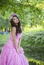 Charming young adult lady with with long hair, make-up and pink flower in spring park. Beauty woman portrait Royalty Free Stock Photo