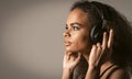 Charming young African-American girl listening her favourite track in headphones wearing red jacket black top under Royalty Free Stock Photo