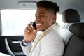 Charming young african american man sitting in backseat of car and talking with cellphone Royalty Free Stock Photo