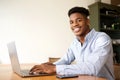 Charming young african american man working with laptop computer at office