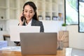 Charming Asian businesswoman or female secretary talking on the phone with business partner Royalty Free Stock Photo