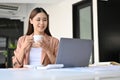 Charming young Asian businesswoman relaxes while sipping morning coffee at her office desk Royalty Free Stock Photo