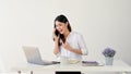 A charming Asian businesswoman is talking on the phone with a client while working at her desk Royalty Free Stock Photo