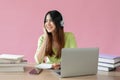 A charming young Asian female college student enjoys listening to music at her study table Royalty Free Stock Photo