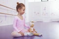 Cute little ballerina girl exercising at dance school