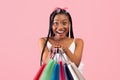 Charming young black woman with afro bunches holding lots of shopping bags on pink studio background Royalty Free Stock Photo