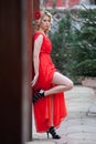 Charming young blonde in red dress with red flower in hair posing against wooden wall.Sensual gorgeous young woman Royalty Free Stock Photo