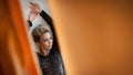 Charming young blonde woman in black blouse posing provocatively, photo through orange curtains. gorgeous young woman Royalty Free Stock Photo