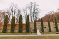 Charming young bride in candid gown and fur jacket on the lane at the autumn park inside fortified castle walls