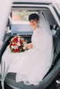 Charming young bride with her bridal bouquet in wedding car limousine Royalty Free Stock Photo